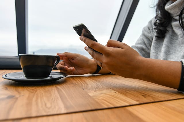 Person texting while holding cup of coffee