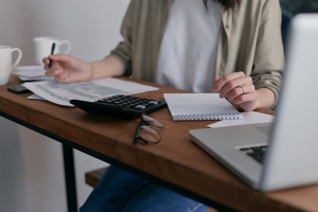 person doing taxes using calculator and computer